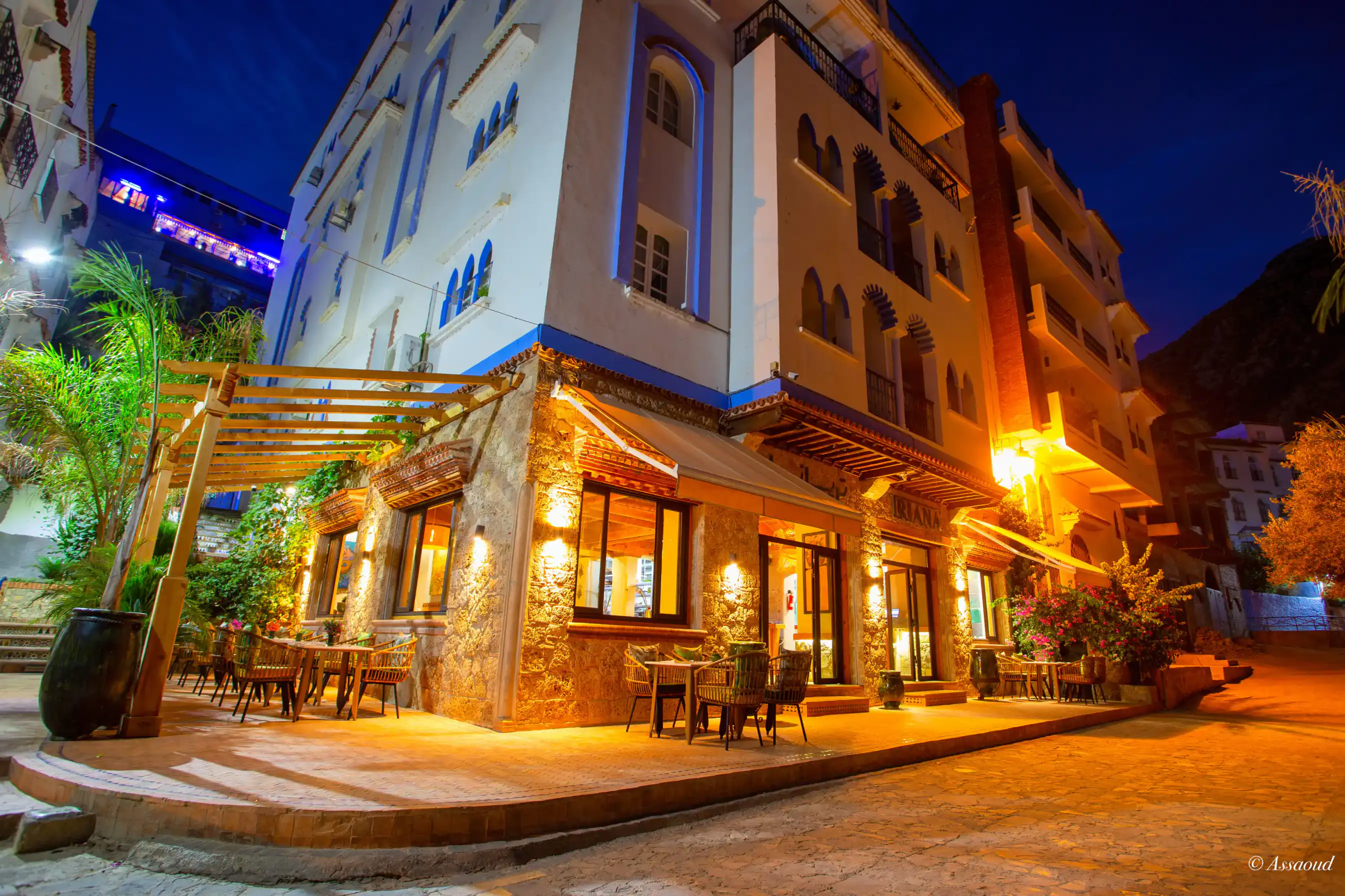 Triana restaurant exterior at night — warm golden lights and stone facade in Chefchaouen